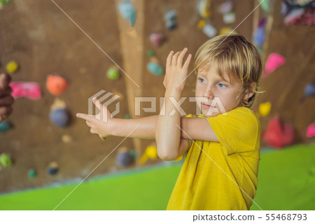 The boy is warming up before climbing a rock wall indoor 55468793