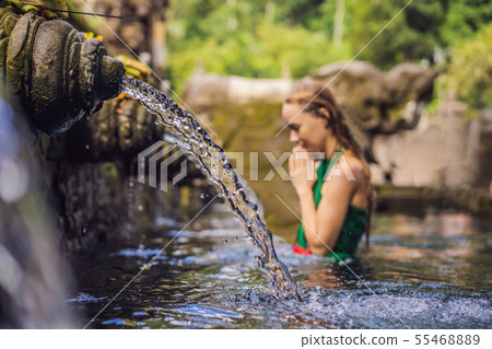 Woman in holy spring water temple in bali. The temple compound consists of a petirtaan or bathing Woman in holy spring water temple in bali. The temple compound consists of a petirtaan or bathing 55468889