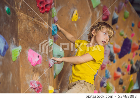 little boy climbing a rock wall in special boots. indoor little boy climbing a rock wall in special boots. indoor 55468898