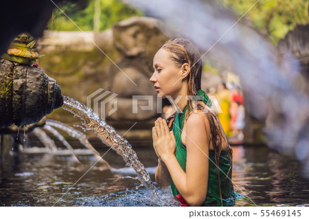 Woman in holy spring water temple in bali. The temple compound consists of a petirtaan or bathing 55469145