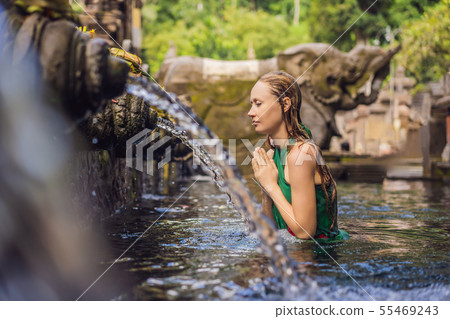 Woman in holy spring water temple in bali. The temple compound consists of a petirtaan or bathing 55469243