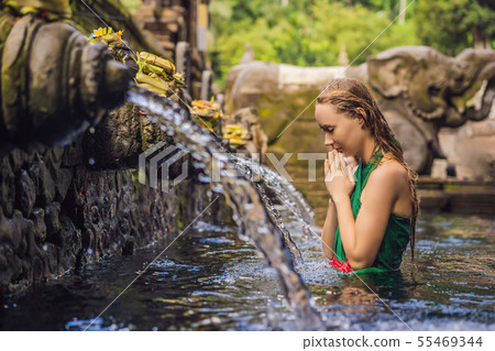 Woman in holy spring water temple in bali. The temple compound consists of a petirtaan or bathing Woman in holy spring water temple in bali. The temple compound consists of a petirtaan or bathing 55469344