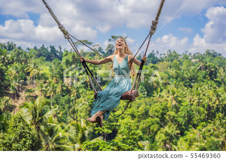 Young woman swinging in the jungle rainforest of Bali island, Indonesia. Swing in the tropics 55469360