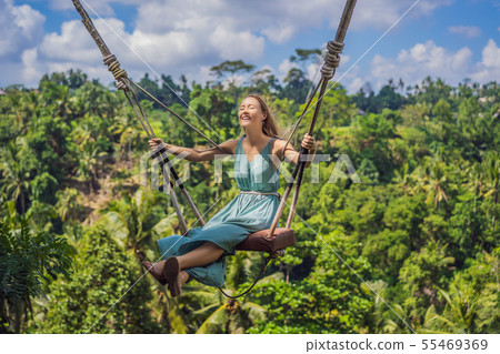 Young woman swinging in the jungle rainforest of Bali island, Indonesia. Swing in the tropics 55469369