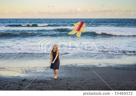 A young woman launches a kite on the beach. Dream, aspirations, future plans 55469372