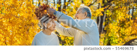BANNER, LONG FORMAT Happy old couple having fun at autumn park. Elderly man wearing a wreath of BANNER, LONG FORMAT Happy old couple having fun at autumn park. Elderly man wearing a wreath of 55469678
