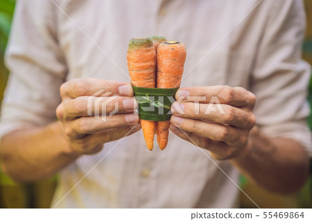 Eco-friendly product packaging concept. Carrot wrapped in a banana leaf, as an alternative to a Eco-friendly product packaging concept. Carrot wrapped in a banana leaf, as an alternative to a 55469864