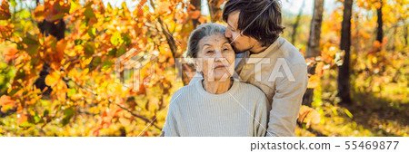 Grandmother and adult grandson hugging in autumn park BANNER, LONG FORMAT Grandmother and adult grandson hugging in autumn park BANNER, LONG FORMAT 55469877