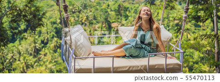 Young woman swinging in the jungle rainforest of Bali island, Indonesia. Swing in the tropics Young woman swinging in the jungle rainforest of Bali island, Indonesia. Swing in the tropics 55470113