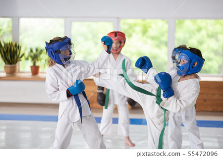 Boy and girl wearing helmets and boxing gloves having a fight 55472096