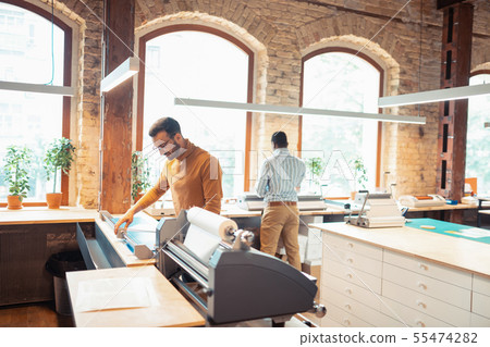 Dark-haired man standing near modern printing technique 55474282