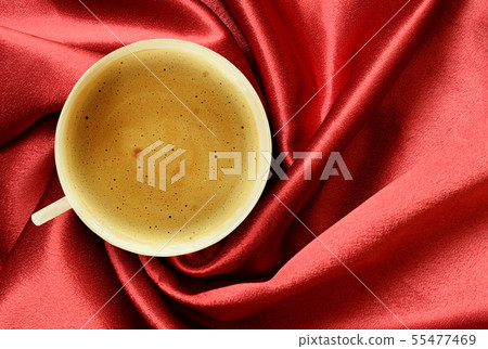 Cup of coffee on folded red silk textile Cup of coffee on folded red silk textile 55477469