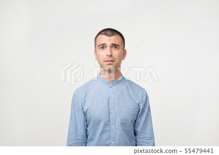 Close up of a doubtful young man in blue shirt. Close up of a doubtful young man in blue shirt. 55479441