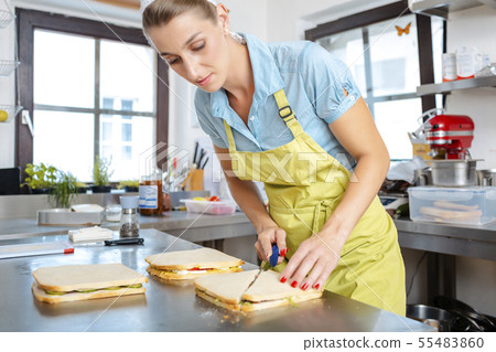 Close-up of a female chef cutting sandwich Close-up of a female chef cutting sandwich 55483860