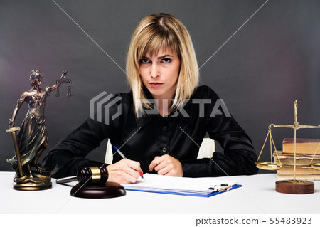 A young fair woman judge works in her office. A young fair woman judge works in her office. 55483923