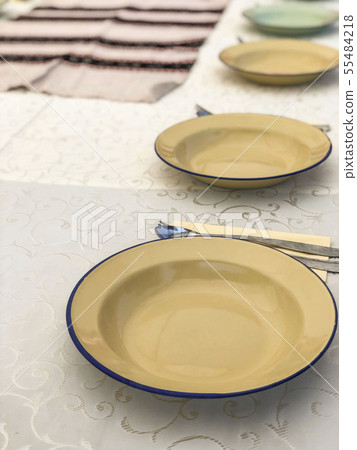 row of empty enamel plates on a table 55484218