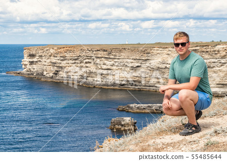 Happy young man on top of cliff enjoying view of Happy young man on top of cliff enjoying view of 55485644