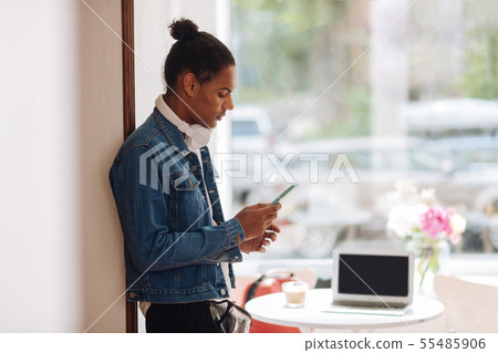 Serious dark-skinned man staring at his telephone 55485906