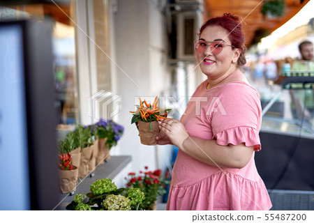 Young and fat woman holding flower pot Young and fat woman holding flower pot 55487200