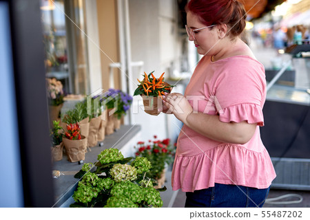 Fat and young woman holding flower pot Fat and young woman holding flower pot 55487202