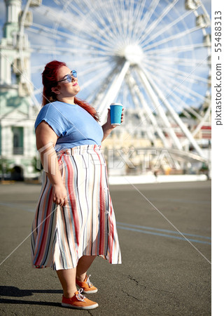 Fat young woman walking on street with coffee cup 55488313