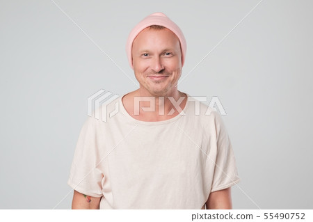 Happy young guy in pink hat looking at camera  55490752