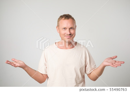 Mature man in white shirt shrugging shoulders   55490763