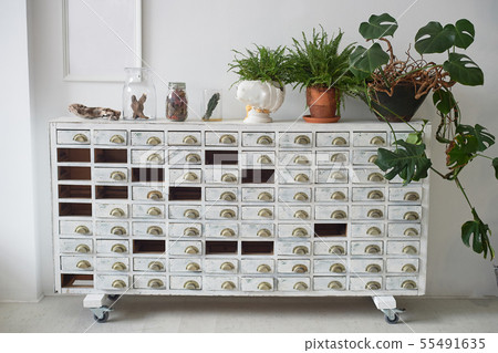 White filing Cabinet in the old style.With missing drawers . On top are pots of flowers. Retro. White filing Cabinet in the old style.With missing drawers . On top are pots of flowers. Retro. 55491635
