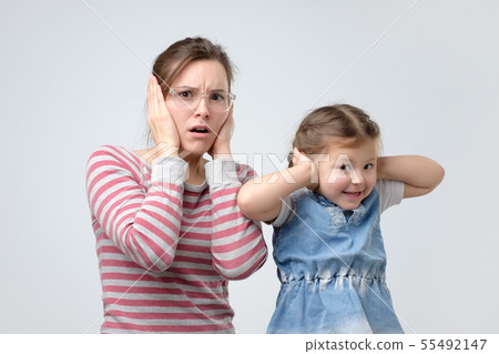 woman and her little daughter cover ears woman and her little daughter cover ears 55492147