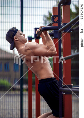Brutal athletic man making pull-up exercises on a crossbar. 55492320