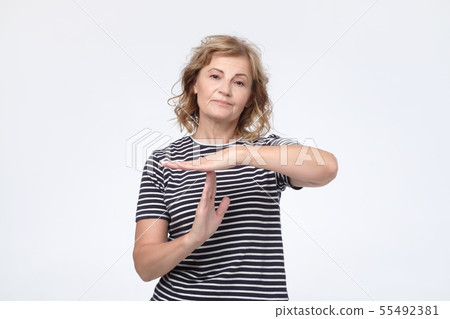 Serious worried mature woman showing time out sign 55492381