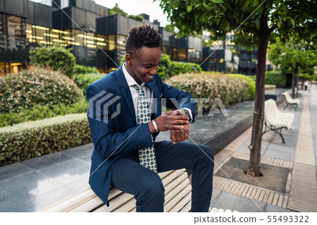 Businessman looking at his watch in office Businessman looking at his watch in office 55493322