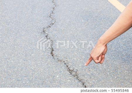 hand finger pointing inspect cracked asphalt road 55495846