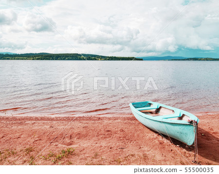 Blue fishing boat anchored on beach sand of lake. Blue fishing boat anchored on beach sand of lake. 55500035