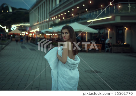 Young woman walks wrapped in a blanket. Young woman walks wrapped in a blanket. 55501770