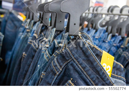 Closeup many jeans hanging on a rack. Row of pants Closeup many jeans hanging on a rack. Row of pants 55502774