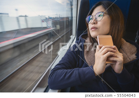 Asian Young lady passenger Sitting in a depressed mood beside the window inside Train which travel between town when travel alone for escape the chaos, traveller and depress concept 55504043
