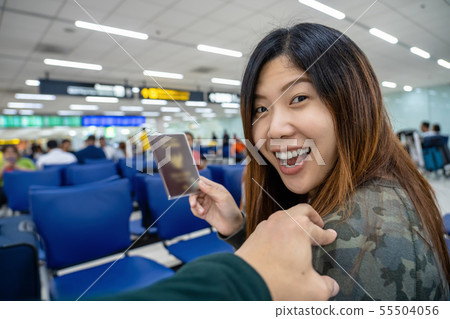 Hand touching on the asian shoulder for greeting friend at the airport when waiting flight on board, hand holding passport with big baggage, traveler and friendly concept 55504056