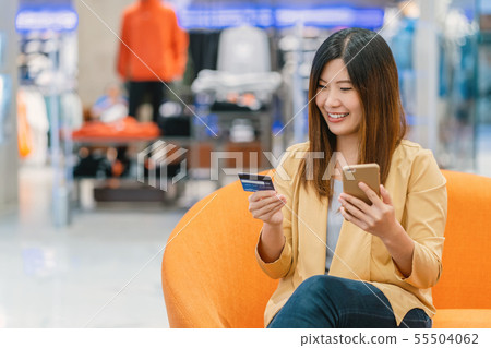 Asian woman using credit card with mobile phone for online shopping in department store over the clothes shop store background, technology money wallet and online payment concept, credit card mockup Asian woman using credit card with mobile phone for online shopping in department store over the clothes shop store background, technology money wallet and online payment concept, credit card mockup 55504062