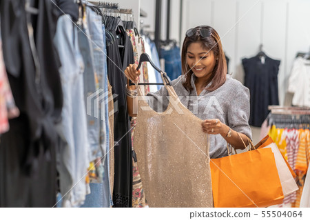 Happy Asian woman choosing clothes with in store shop with happy action at department center Happy Asian woman choosing clothes with in store shop with happy action at department center 55504064