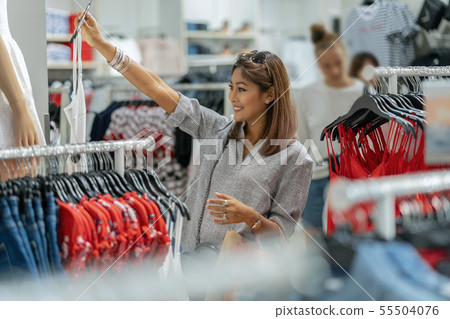 Happy Asian woman choosing clothes with reflection of glass in shop store shop with happy action at department center Happy Asian woman choosing clothes with reflection of glass in shop store shop with happy action at department center 55504076