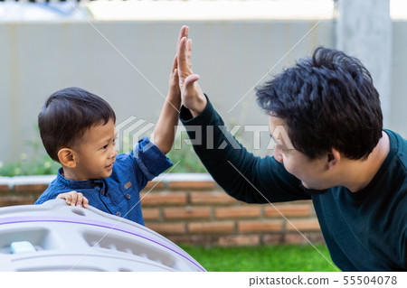 Asian single dad with son are playing and give me five together when living in front lawn for Self learning or home school, Family and single father concept, selective focus Asian single dad with son are playing and give me five together when living in front lawn for Self learning or home school, Family and single father concept, selective focus 55504078