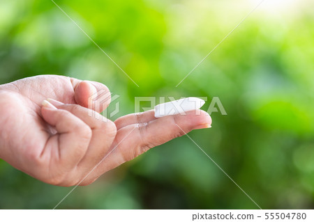 Hand holding suppository candle on green nature light blur background Hand holding suppository candle on green nature light blur background 55504780