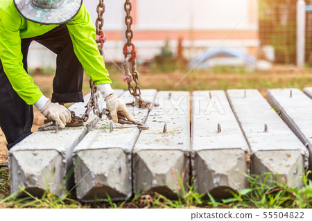 Construction worker unloading concrete stake from truck. 55504822
