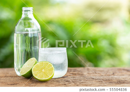 Glass of iced lemon soda on wooden table with green blur space for text or design 55504836