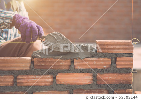 Worker installing bricks wall in process of house building Worker installing bricks wall in process of house building 55505144