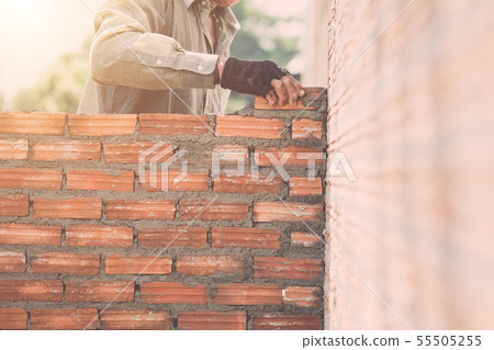 Worker installing bricks wall in process of house building 55505255