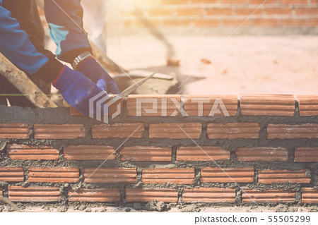 Worker installing bricks wall in process of house building Worker installing bricks wall in process of house building 55505299