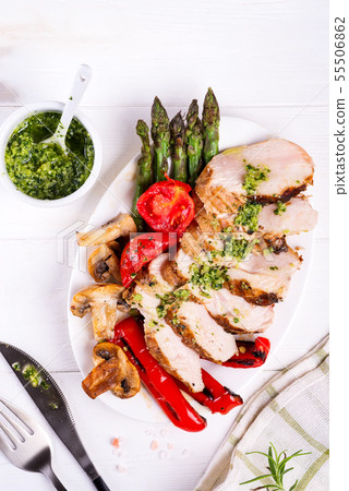 Grilled chicken breast on a plate with tomatoes, asparagus and mushrooms on a wooden background 55506862