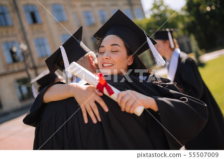 Two happy groupmates hugging at their graduation party. 55507009